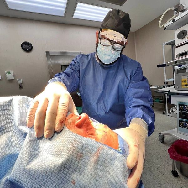 Surgeon performing a delicate procedure on a patient's face in an operating room.