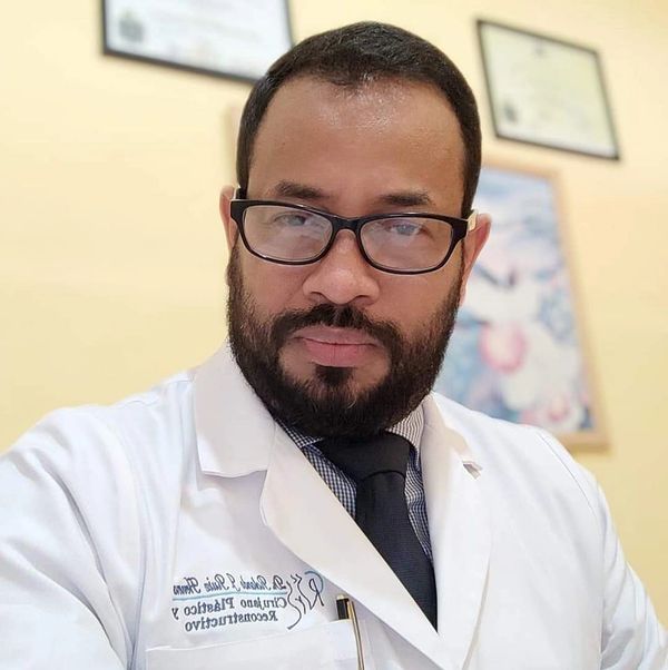 Man in a white lab coat with glasses and a beard.
