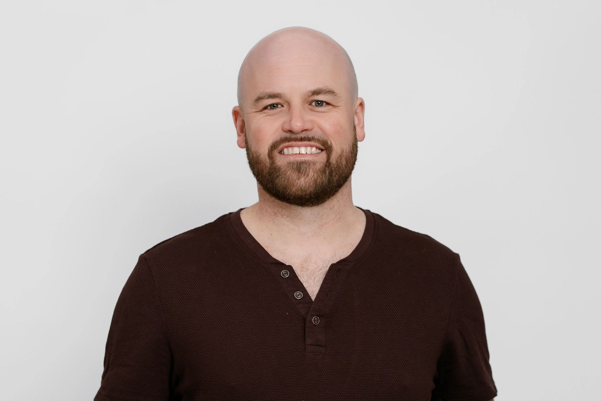 Smiling bald man with a beard in a dark shirt.