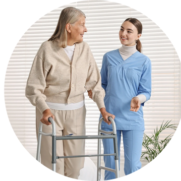 A nurse assists an elderly woman using a walker indoors.