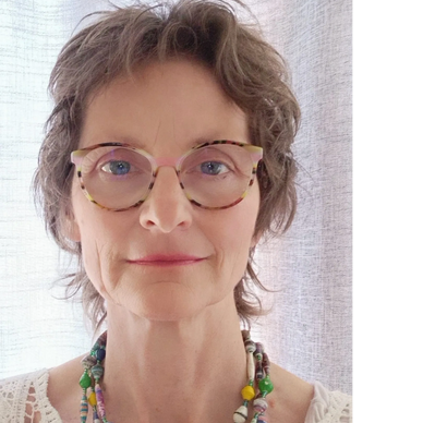 Woman with short hair and colorful necklace smiling gently.