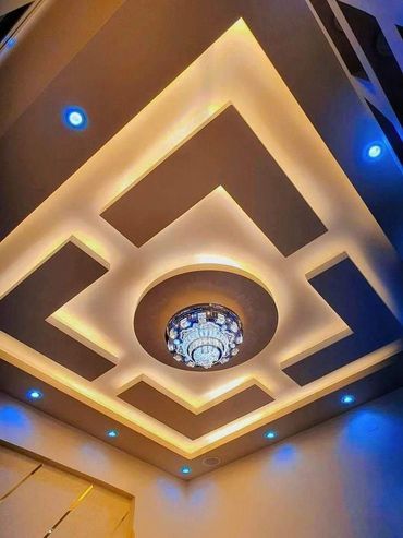 Modern ceiling design with geometric lighting and a central chandelier.