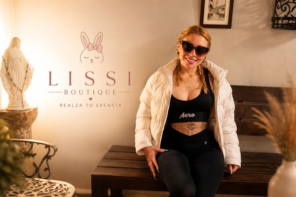 Woman in sporty outfit and white jacket posing inside Lissi Boutique.