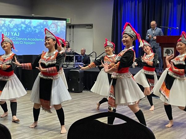 Image of seven girls dancing in traditional Hmong attire.