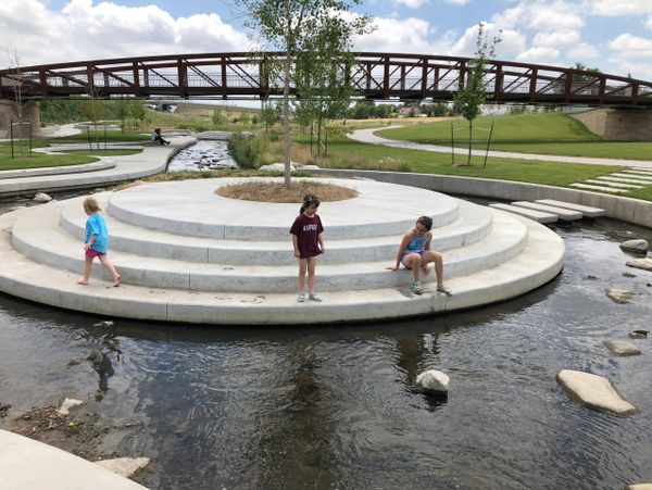 Three children sitting and walking on concrete steps in Little Dry Creek in Westminster.