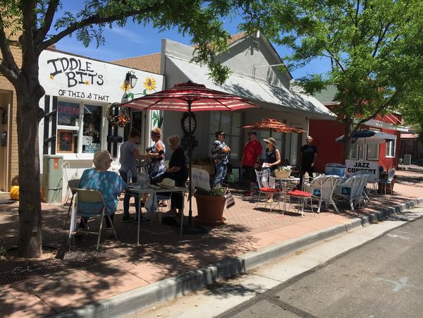 People sitting and standing along the sidewalk outside of Westminster's historic 73rd Avenue.