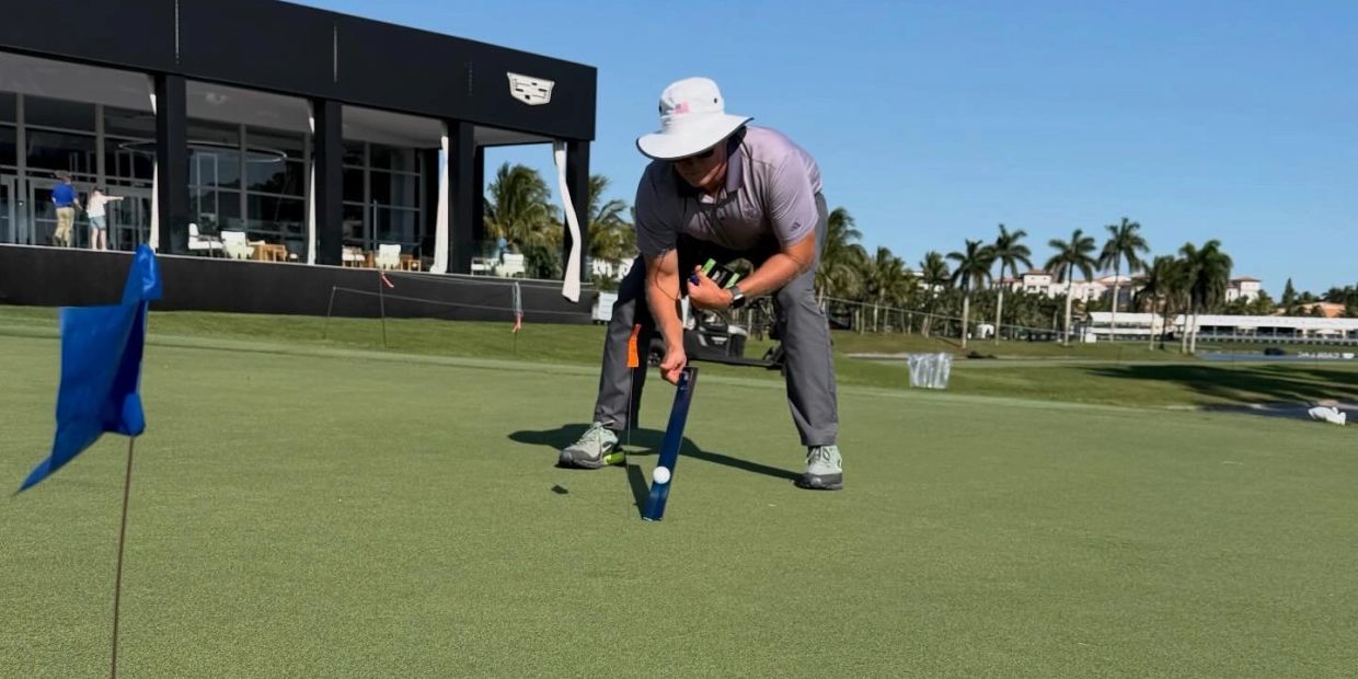 A person using a device to analyze a golf ball on a green.