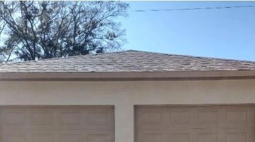 A beige two-car garage with closed doors and a basketball hoop.