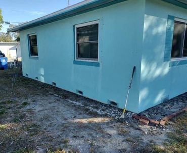 A light blue house exterior with windows and a golf club leaning against the wall.