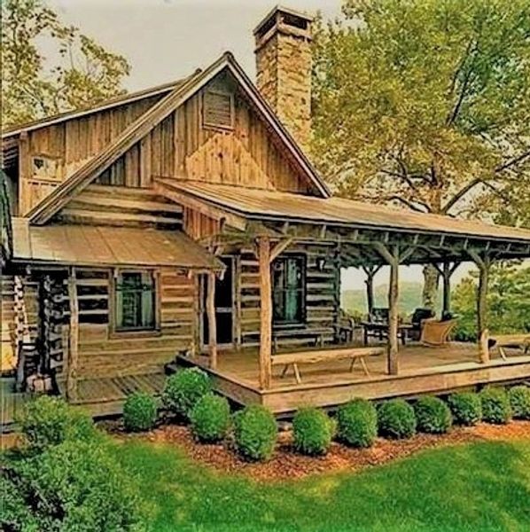 Rustic wooden cabin with a porch and greenery.