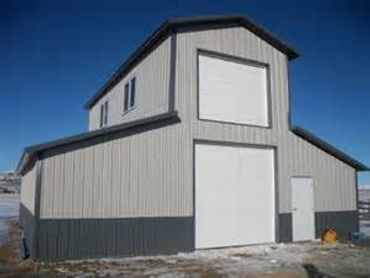 A gray barn with large white doors.