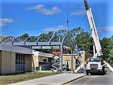 Crane lifting steel structure frame at construction site.