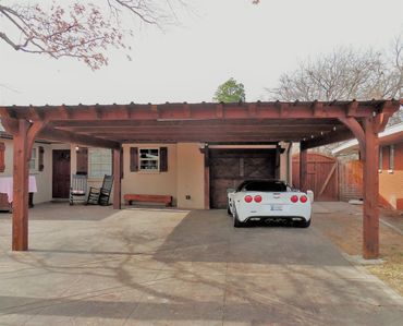 Custom framed pergola carport structure with a sheet metal top canopy cover.