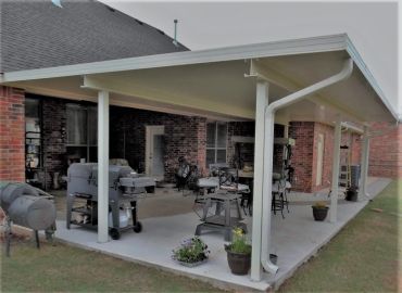 Covered patio with grill and seating area.