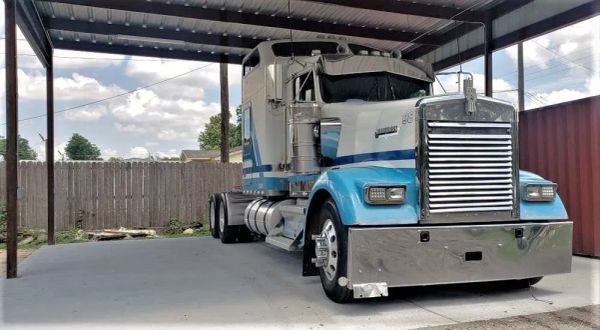 Large blue and white semi truck parked in covered area.
