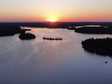 Aerial drone photo of lake surrounded by forest and during sunset in Minnesota.