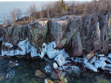 Aerial drone photo of Lake Superior cliff with ice formation and trees in Minnesota.