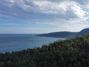 Drone photo of Lake Superior and green forested hills.