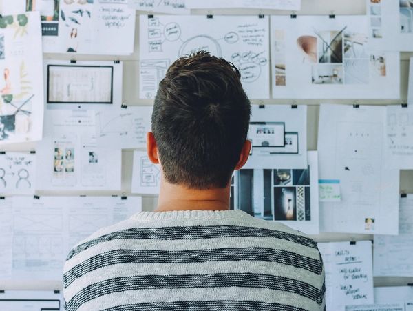 Man looking at board with many drawings on paper on it
Photo by Pexels from Pixabay