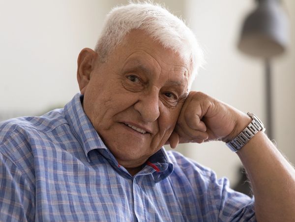 Portrait of happy old 80s man in casual looking at camera, smiling, posing at home.