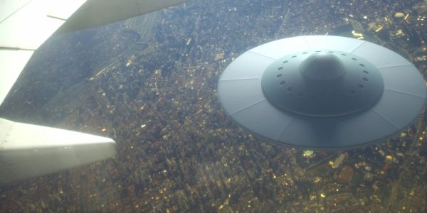 UFO flying over a city as seen from an airplane window.