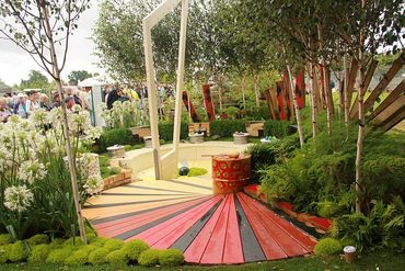 A colorful garden with a circular wooden platform and lush greenery.