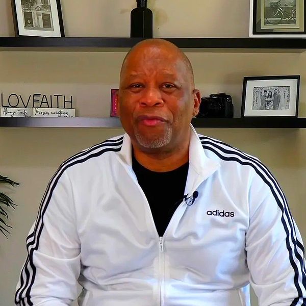 Man in white Adidas jacket sitting indoors.