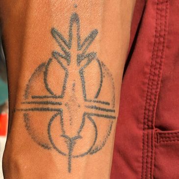 A tan toned arm extends to show their imprint of a hummingbird crop circle