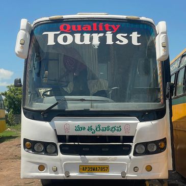 Front view of a white tourist bus with 'Quality Tourist' sign on windshield.
