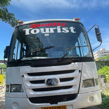 Front view of a white tourist bus with a clear blue sky.
