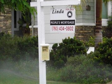 A picture of a single post panel sign with  a realtor sign installed. 