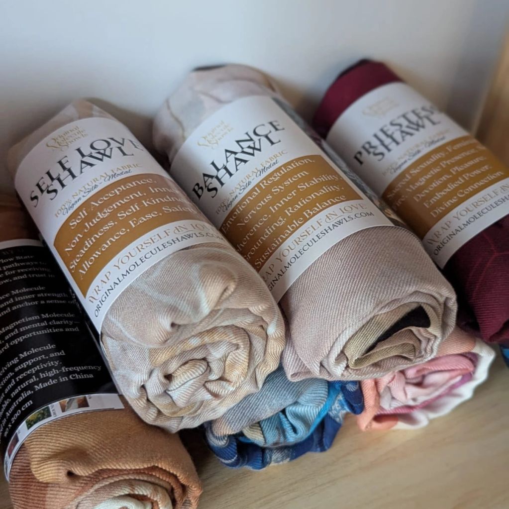 Rolled shawls with labels on a wooden surface.