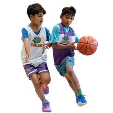 Two boys playing basketball, one in white and one in purple jersey.
