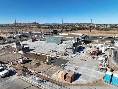 Construction site with workers pouring concrete under clear blue sky.