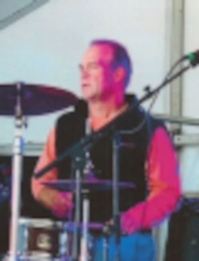 A man playing drums on stage during a live performance.