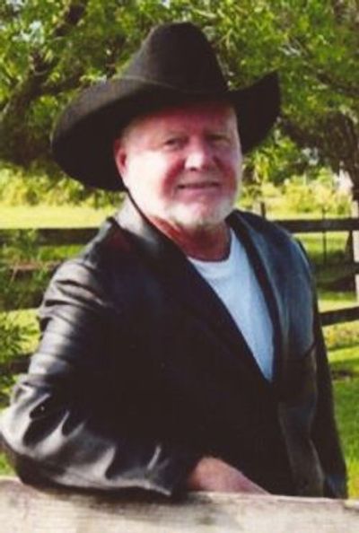 Man in a black cowboy hat and leather jacket outdoors.