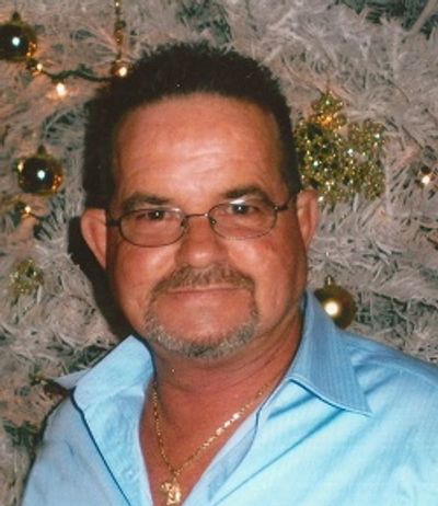 Man with glasses and a goatee in front of a decorated Christmas tree.