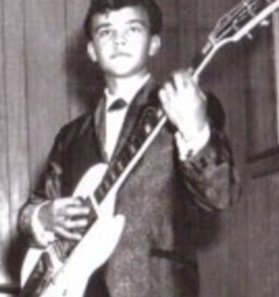 Black and white photo of a young man playing an electric guitar.