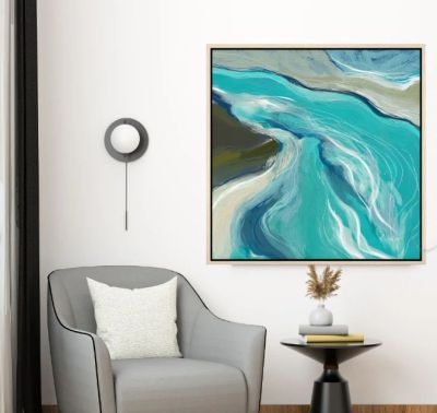 Modern gray armchair with a white pillow, round side table, and blue abstract painting.