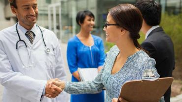Doctor and woman shaking hands outdoors.