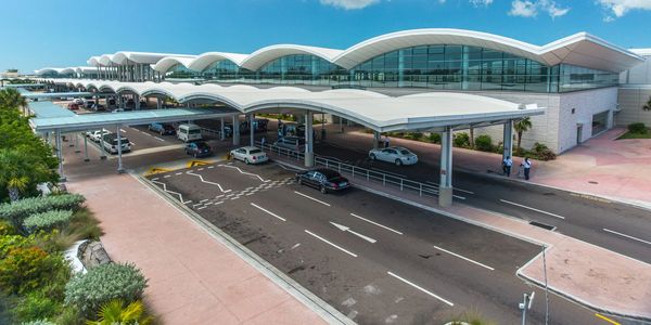 Modern airport terminal with cars and blue skies.