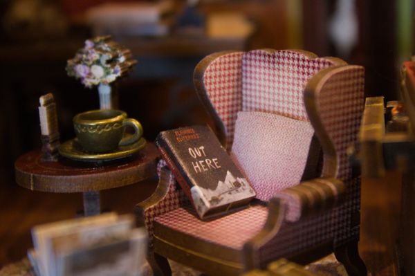 Miniature cozy reading nook with armchair, book, and tea set.