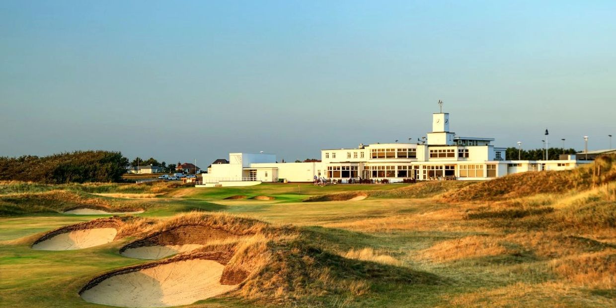 Golf course with clubhouse under clear sky.