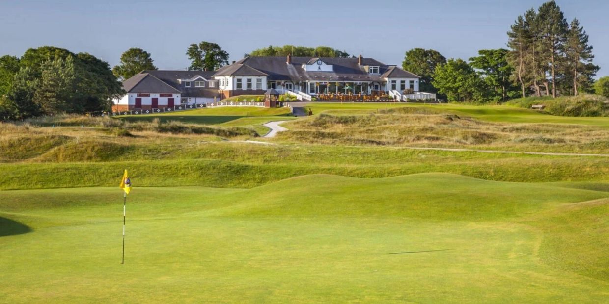 Golf course green with clubhouse in the background.