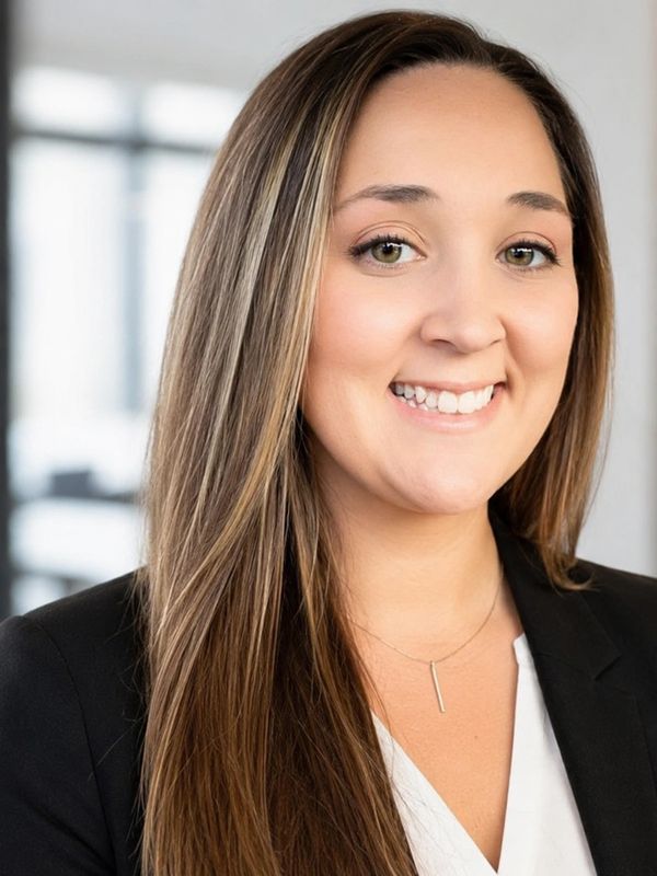Professional woman smiling, wearing a black blazer and white blouse.