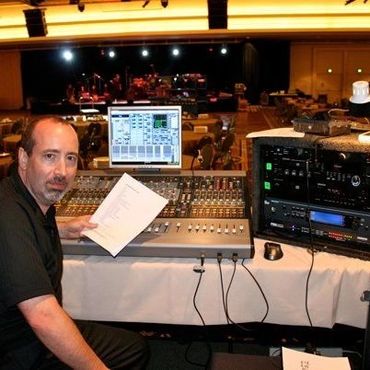 Audio engineer at a sound mixing console during a live event setup.