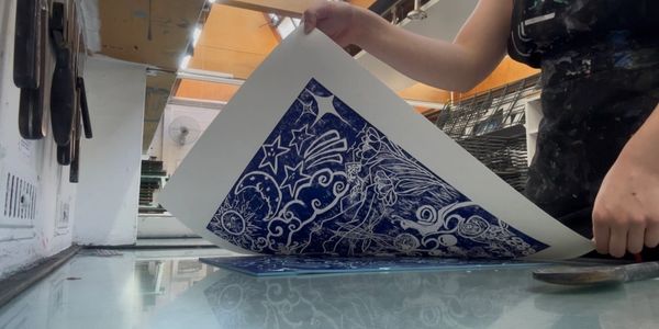 Artist peeling back blue print with star and sea patterns.