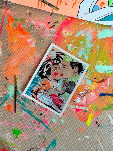 A comic-style print of a couple kissing with paint splatters on a canvas background.