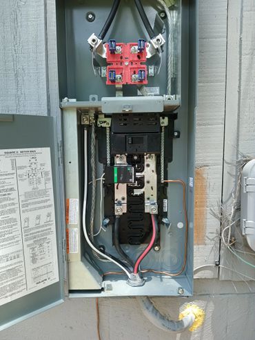Open electrical meter main panel with wiring and circuit breaker inside.