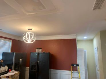 Modern kitchen with black appliances and a unique ceiling light fixture.